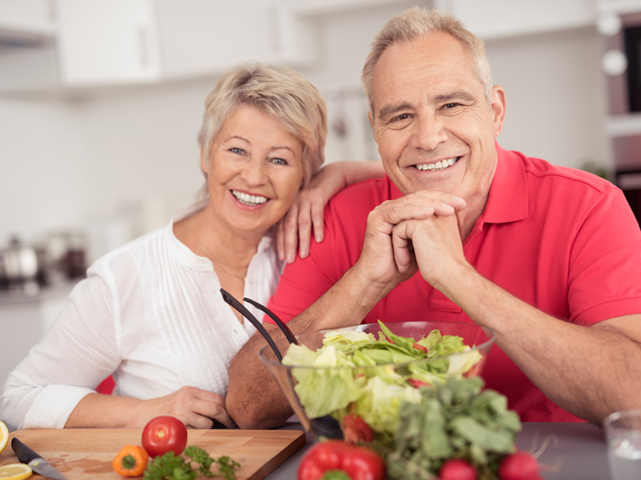 Active adult couple in kitchen cooking